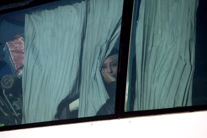 Una mujer mira por la ventana de un autobús mientras deja el campamento de refugiados.