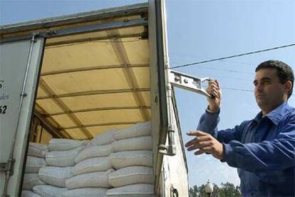 Un operario abre el camión para descargar maíz ante la Fundación Asilo de San Castor.