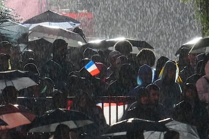 Espectadores esperan bajo la lluvia, durante la jornada inaugural este viernes en París.