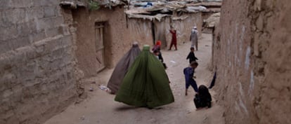 Dos mujeres caminan  al tiempo que unos niños juegan en una calle de Islamabad, Pakistán.