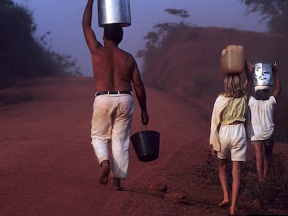 Un padre y sus hijos llevan cubos de agua en la carretera Transamazónica, Estado de Pará, Amazonas al norte de Brasil.