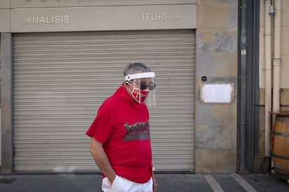 Un hombre con mascarilla y visera de protección y vestido con los colores de San Fermín en una calle céntrica de Pamplona, el 6 de julio.