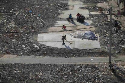 Un niño barre una zona llena de escombros donde serán construidos unos rascacielos en el centro de Shanghái (China).