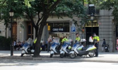 Cuatro agentes de la Guardia Urbana con sus motocicletas estacionadas sobre la acera