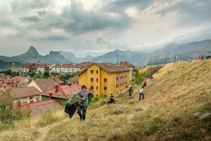 Los Picos de Europa, al fondo, mientras los vecinos realizan labores de limpieza y desbroce del campo.