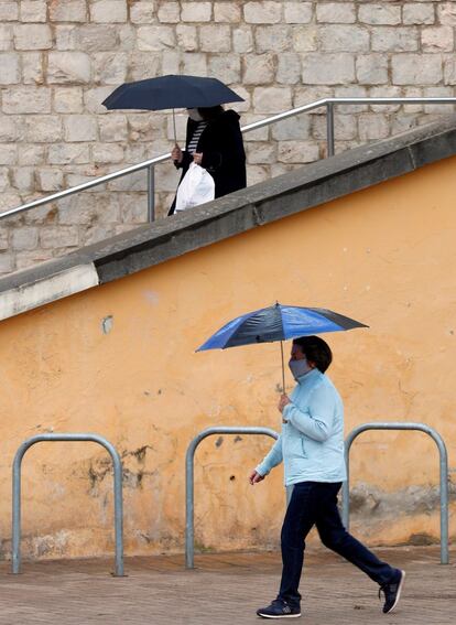 Dos personas se protegen de la lluvia con paraguas, en Valencia.