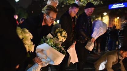 Los cuatro miembros de U2, colocando flores en las inmediaciones de la sala Bataclan.