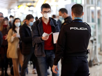 Un agente de la policía controla el paso de viajeros en el aeropuerto de Barajas, en Madrid, el 19 de marzo.