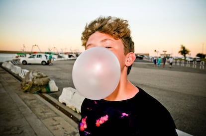 Un niño masca un chicle frente a un puerto pesquero.