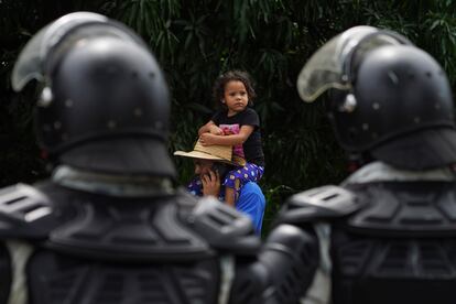 Migrants walk past members of the Mexican National Guard on their way north on the Huixtla road in Chiapas state, Mexico, Wednesday, June 7, 2022. The group part oa a larger migrant caravan, left Tapachula on Monday, tired of waiting to normalize their status in a region with little work and still far from their ultimate goal of reaching the United States. (AP Photo/Marco Ugarte)