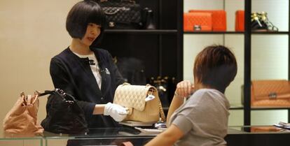 Una dependienta muestra un bolso a una clienta en una tienda de Chanel en Shangh&aacute;i. 