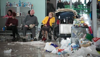 Tres turistas descansan en la T1 entre montanas de basuras.