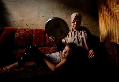 Una mujer palestina abanica a su hija en medio de una ola de calor e importantes cortes de energía en la ciudad de Gaza, el lunes.