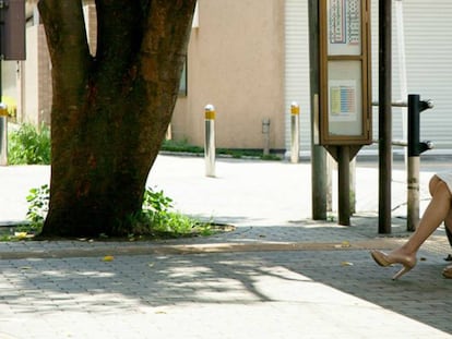 Una mujer espera en una parada de autobús.