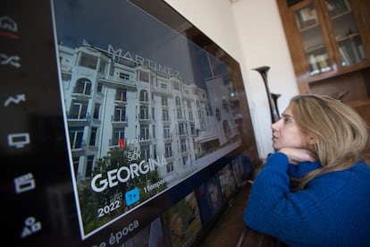 A young woman sits in front of a very large television in her home in Madrid.