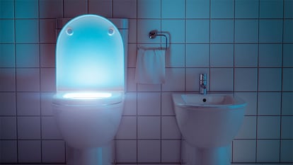 Un inodoro y un bidé iluminados por la noche en un cuarto de baño.