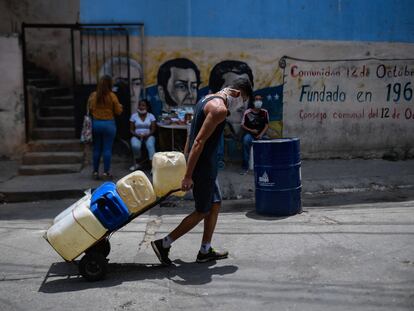 Un hombre tira de una carretilla cargada de bidones de agua en el barrio de Petare en Caracas, el 19 de mayo de 2020.
