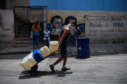 Un hombre tira de una carretilla cargada de bidones de agua en el barrio de Petare en Caracas, el 19 de mayo de 2020.