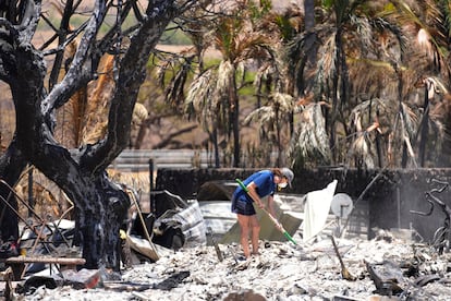 A woman digs through rubble of a home destroyed by a wildfire on Friday, Aug. 11, 2023, in Lahaina, Hawaii. 