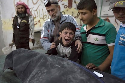 Un niño es consolado mientras llora al lado del cuerpo de un pariente que murió en un ataque aéreo en la ciudad siria de Alepo, el 27 de abril de 2016.