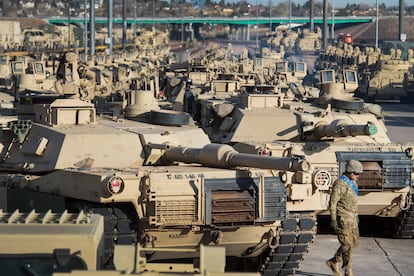 A soldier walks past a line of M1 Abrams tanks