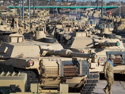 A soldier walks past a line of M1 Abrams tanks