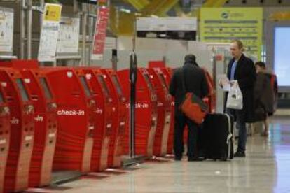 Varios pasajeros junto a unos mostradores de facturación automáticos ayer en la T4 del aeropuerto de Barajas.