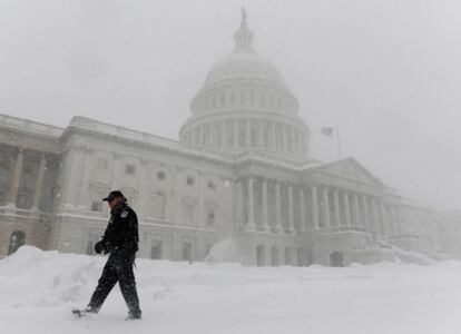 Un policía patrulla junto al Capitolio hoy en un Washington DC cubierto de un manto blanco y helado
