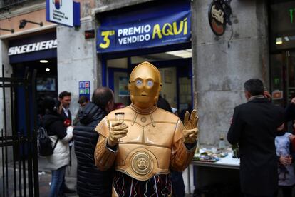 Una persona disfrazada del robot de la Guerra de las Galaxias C-3PO celebra en la administración de lotería 150 en la calle Arenal de Madrid, donde se ha vendido una serie del tercer premio.