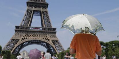 Varios turistas se protegen con sombrillas del calor, frente a la Torre Eiffel de Par&iacute;s, Francia. 