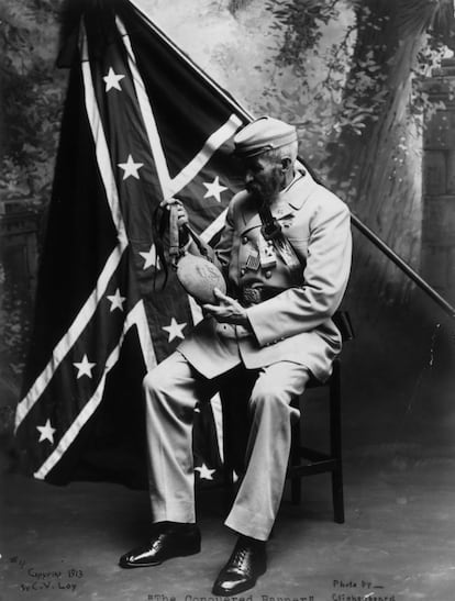 Un veterano del bando confederado, en 1875, con su bandera detrás, observa una botella de agua del ejército enemigo, el de la Unión.