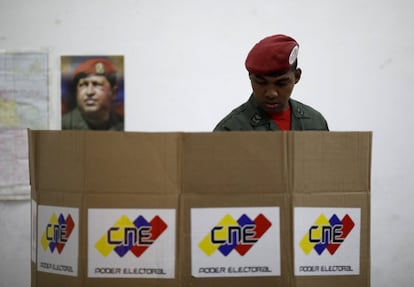 Un soldado venezolano con una imagen de Hugo Chavez detrás de él en un centro electoral este domingo.