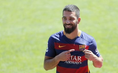 Arda Turan se&ntilde;ala su nuevo escudo en la presentaci&oacute;n.