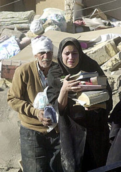 Dos habitantes del pueblo de Changooreth, junto a su casa destruida.