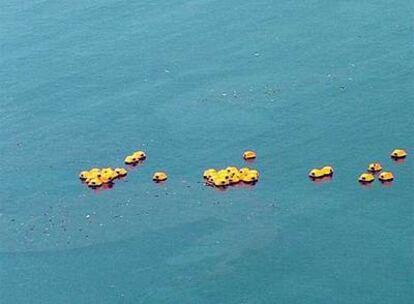 Los botes salvavidas del <i>Sea Diamond</i> flotan tras su hundimiento entre restos fuel. .