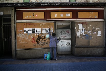 Una mujer coloca carteles en el antiguo escaparate de un local de la calle Mesones, una de las históricas del comercio en Talavera. Los negocios cerrados aparecen por doquier, junto a viejos carteles de "se alquila" o "se vende".