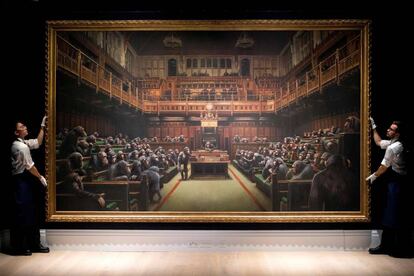 Dos trabajadores de Sotheby's muestran el cuadro 'Devolved Parliament' a los asistentes de la subasta.