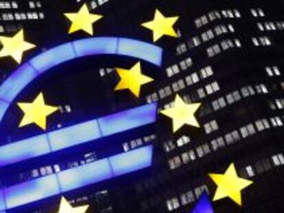 La foto muestra un signo de euro iluminado frente a la sede del Banco Central Europeo.