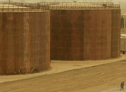 Un soldado pasea delante de un tanque de petróleo en Yusifiya, en el llamado "triángulo de la muerte", situado a unos 16 kilómetros al sur de Bagdad. El inmenso tanque de petroleo no contiene ni una sola gota de petróleo: estas instalaciones petrolíferas comenzaron a construirse por una empresa rusa, suspendida tras el inicio de la invasión de abril 2003.