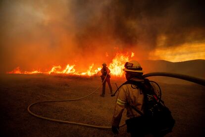 Los bomberos trabajan para controlar las llamas durante el incendio Hughes a lo largo de una carretera en Castaic.