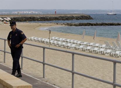 Un policía vigila el acceso a una de las playas de Palma de Mallorca desalojadas ayer por los atentados de ETA.