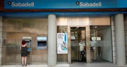 Una mujer usa un cajero automático del Banco Sabadell.