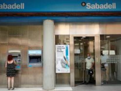 Una mujer usa un cajero automático del Banco Sabadell.