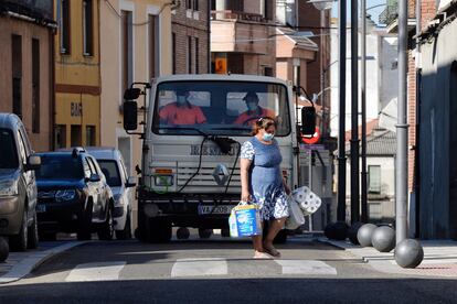 A woman walks in front of a truck tasked with disinfecting the streets of  Íscar, which has been confined for 14 days due to a surge in Covid-19 cases.