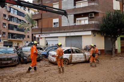 Varios operarios retiran uno de los coches afectados en Paiporta, este viernes.