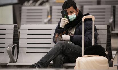 Un jove amb guants i mascareta a l'Estació de Sants, a Barcelona.