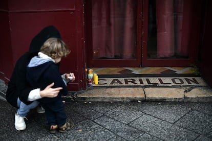 Una mujer acompañada por su hijo dejan unas velas en la entrada del restaurante 'Le Carrillon' en homenaje a las víctimas en el primer aniversario de la masacre en la capital francesa.