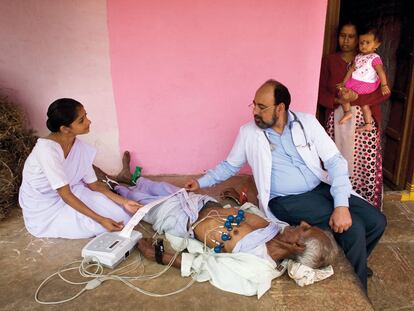 Un médico explora a un paciente con un dispositivo portátil, capaz de atender a los enfermos de las zonas rurales indias.