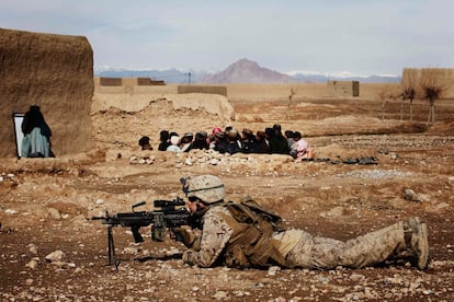 Un soldado toma posiciones, mientras un grupo de niños asiste, como otro día más, a una clase al aire libre en la provincia de Helmand.