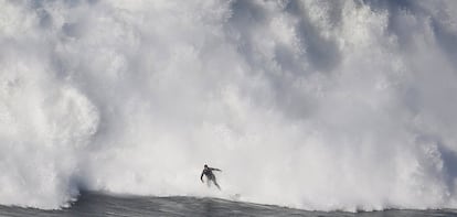 Uno de los surfistas que están este fin de semana en Nazaré intenta escapar de la espuma que forman las olas al romper. Está previsto que, si el mar lo permite, este martes se den cita en esta localidad portuguesa medio centenar de los mejores especialistas del mundo en olas grandes.